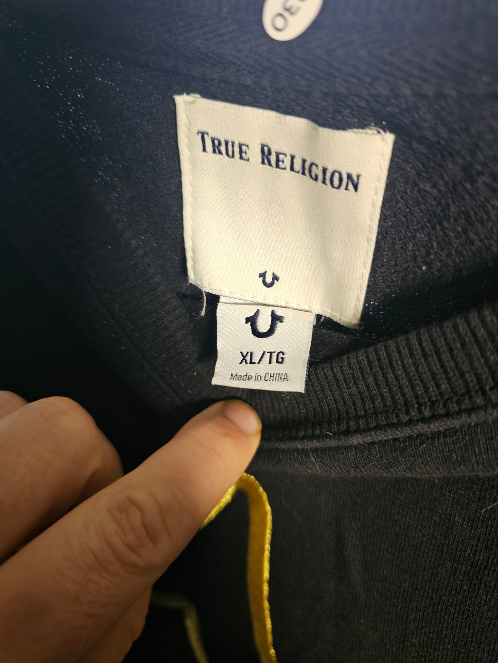 True Religion label on a garment with a hand pointing to it