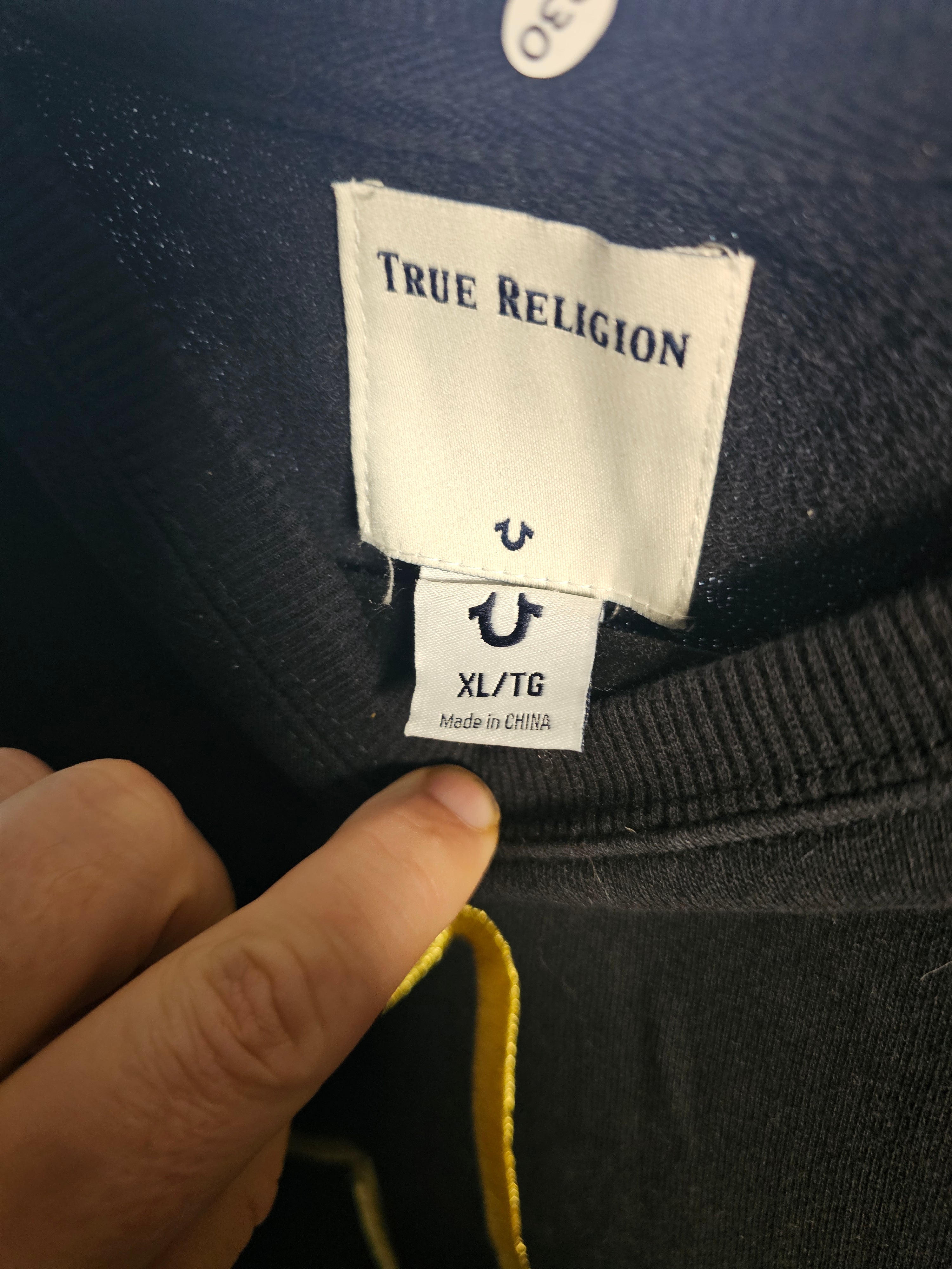 True Religion label on a garment with a hand pointing to it