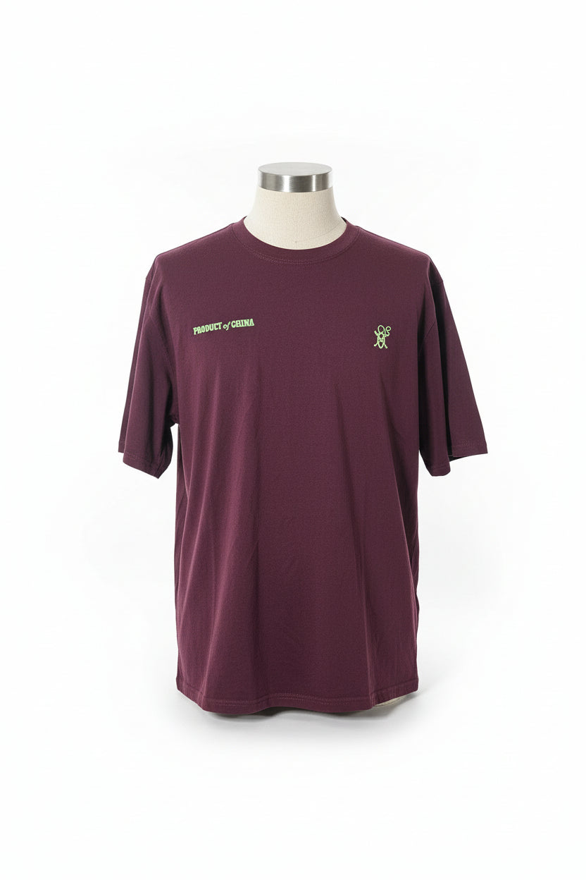 Purple shirt with green logo on a patterned surface