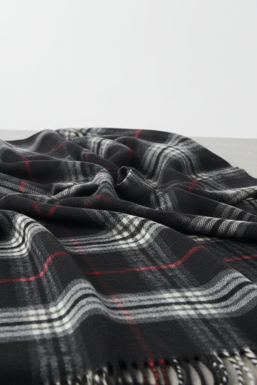 Plaid scarf with black, red, and white pattern on a textured surface